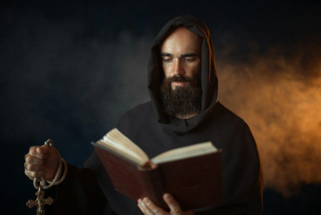 Medieval monk praying with book in church and drinking mead