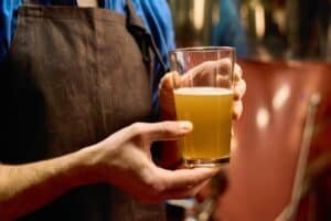 hands of young male brewer in apron showing how to make braggot