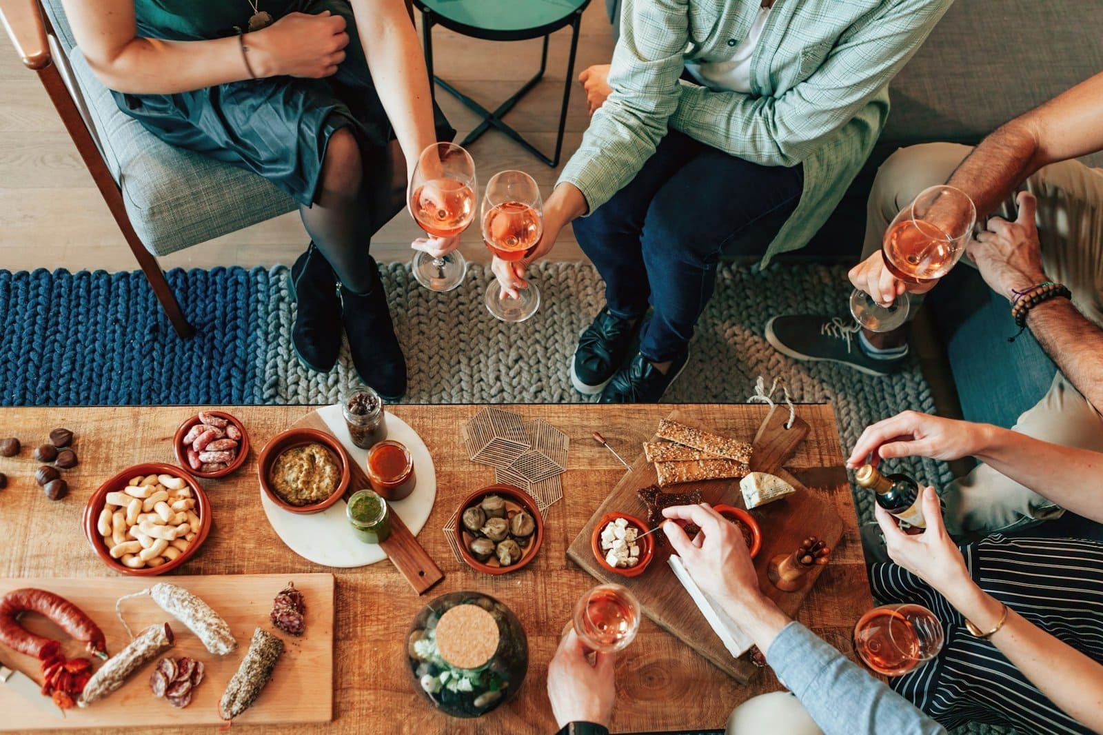 top view of unrecognizable people sitting around the living room table at mead tasting