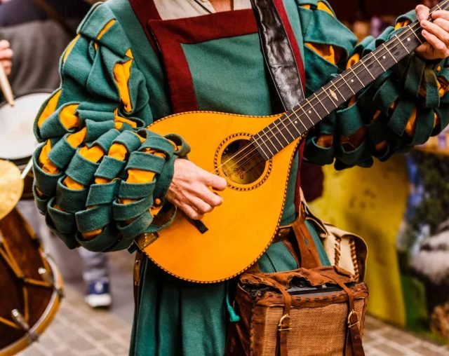 Medieval troubadour playing an antique guitar at mead festivals